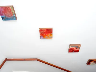White staircase hung with small colourful canvases
